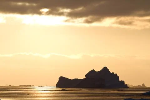 Iceberg in antarctic waters in the rays of the setting sun on a summer evenin Stock Photos