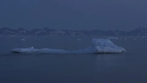 Iceberg on the Arctic Ocean with mountain in the background, Greenland Stock Footage 102511184