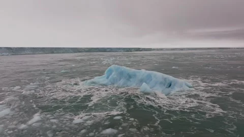 Iceberg floating in the Arctic ocean with massive ice shelf in the horizon Vídeos de archivo 290160339