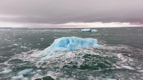 Iceberg floating in the Arctic ocean with massive ice shelf in the horizon Stock Footage 291622339