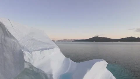 Iceberg floating in the Arctic ocean with massive ice shelf in the horizon 库存影片 291622507