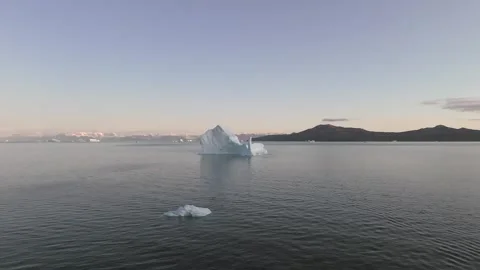 Iceberg floating in the Arctic ocean with massive ice shelf in the horizon Stock Footage 291622557