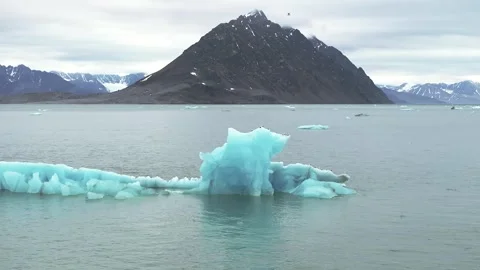 Iceberg floating in the Arctic ocean with massive ice shelf in the horizon Stock-Footage 297533317