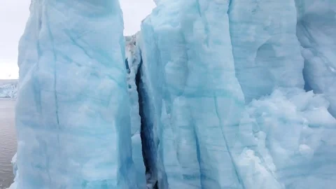 Iceberg floating in the Arctic ocean with massive ice shelf in the horizon Stock-Footage 297533342
