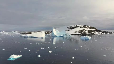 Iceberg floating in the Arctic ocean with massive ice shelf in the horizon 库存影片 303646933