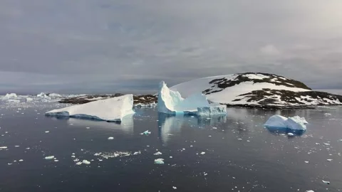 Iceberg floating in the Arctic ocean with massive ice shelf in the horizon 库存影片 303647096