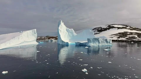 Iceberg floating in the Arctic ocean with massive ice shelf in the horizon 库存影片 303647097