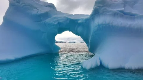 Iceberg floating in the Arctic ocean with massive ice shelf in the horizon 库存影片 303647944