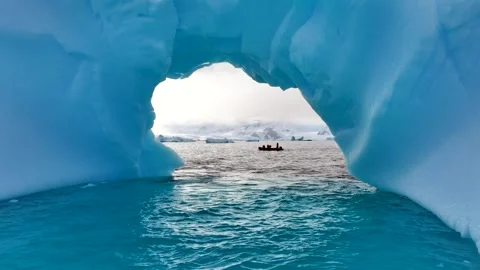 Iceberg floating in the Arctic ocean with massive ice shelf in the horizon 库存影片 303648133
