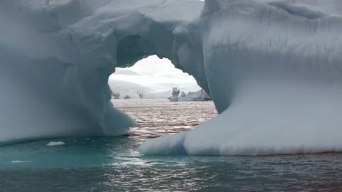 Iceberg floating in the Arctic ocean with massive ice shelf in the horizon 库存影片 303648223