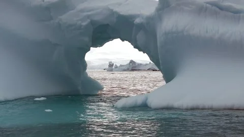 Iceberg floating in the Arctic ocean with massive ice shelf in the horizon 库存影片 303648295
