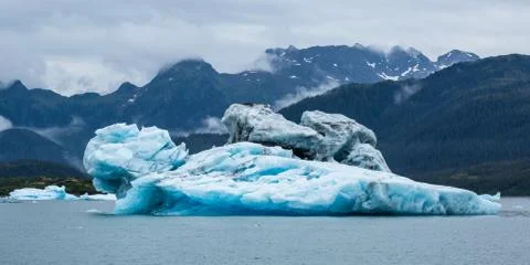 Iceberg floating in front of large peaks in the Prince William Sound near Val Stock Photos