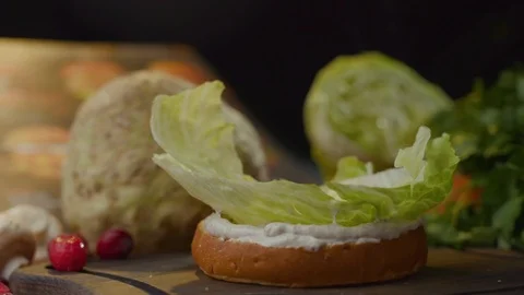 Iceberg lettuce leaf falling on a bun while making a burger. 스톡 동영상 121701862