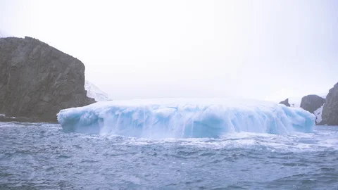 Iceberg melting as it sinks below the ice cold water bobbing up and down Stock Footage 122095665