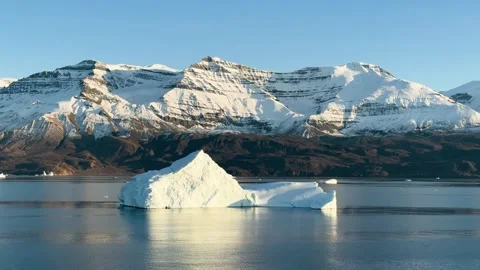Icebergs float in calm water as the sun rises over the mountains in Greenland Vídeo Stock 331304005