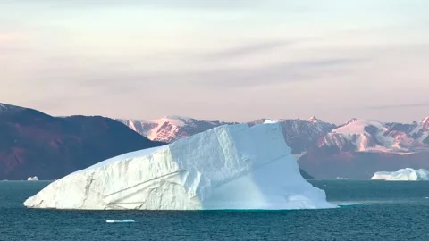 Icebergs float in calm waters of a glacier lagoon surrounded by mountains at sun 库存影片 317931004
