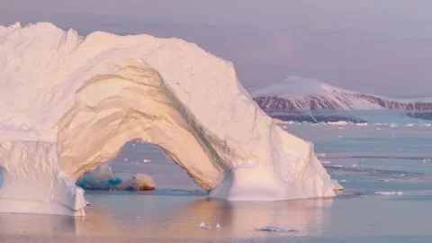 Icebergs float in calm waters of a glacier lagoon surrounded by mountains at sun 库存影片 317931021