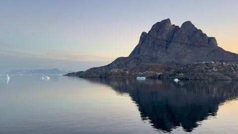 Icebergs float near a mountain at dawn in a quiet Arctic landscape Stock Footage 339998651