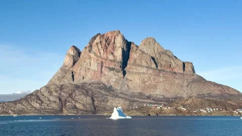 Icebergs float near a mountain at dawn in a quiet Arctic landscape Stock Footage 339998653