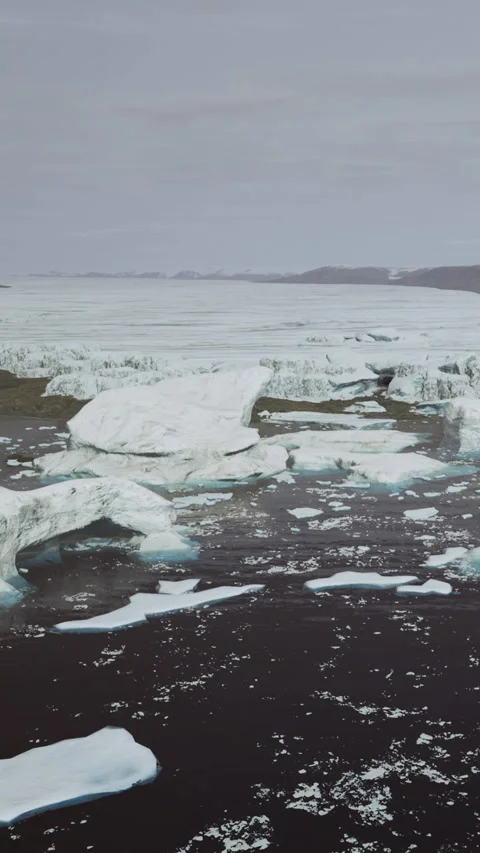 Icebergs float in the ocean with distant land visible in cold weather 库存影片 334723695