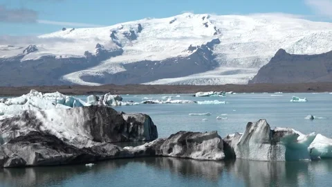 Icebergs float peacefully in a tranquil lagoon under clear blue skies in Iceland 스톡 동영상 321590349