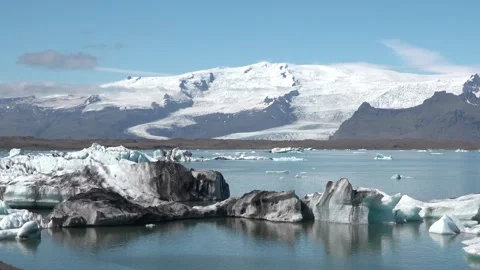 Icebergs float peacefully in a tranquil lagoon under clear blue skies in Iceland 库存影片 321590352