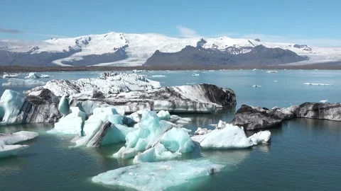 Icebergs float peacefully in a tranquil lagoon under clear blue skies in Iceland 库存影片 321590386