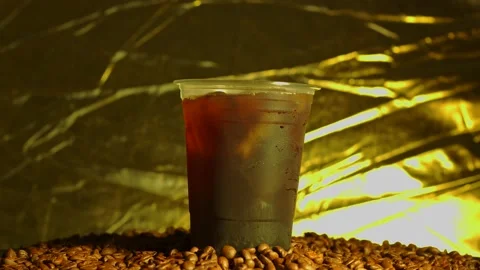 Iced Black Coffee In Disposable Plastic Cup On Roasted Coffee Bean. 库存影片 196776407