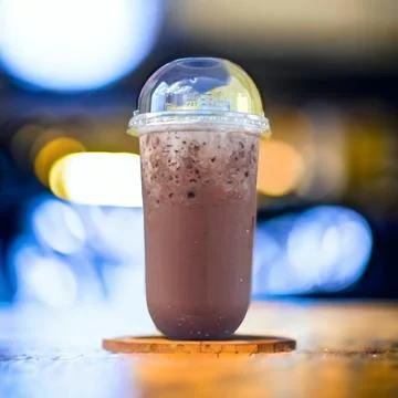 Iced cocoa in a clear plastic cup covered with a hemispherical lid. The bac.. Foto stock