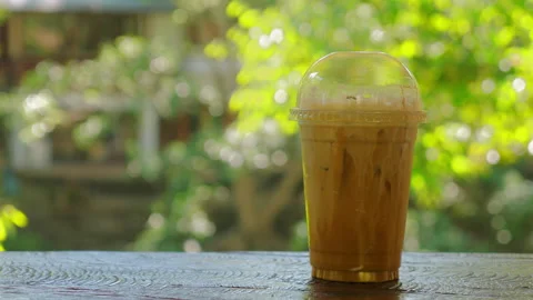 Iced coffee in clear plastic cup with dome lid sitting on outdoor Stock Footage 293495329