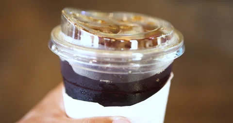 Iced coffee in a clear plastic cup with lid, showing rich layers and ice Video stock 334079207