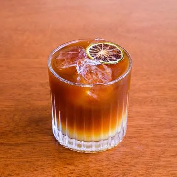 Iced coffee cocktail with lime slice on wooden table Stock Photos