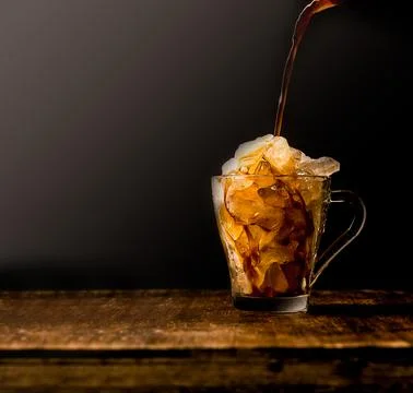 Iced coffee with crashed ice, coffee is pouring, on wooden table top, isolated Stock Photos