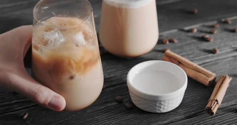 Iced coffee drink, latte with brown ice cubes, milk, cream topping, sprinkled Stock Footage 242293059