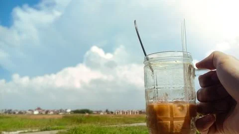 Iced Coffee in Glass Jar Held Against Sunny Cloduy Sky. Фото