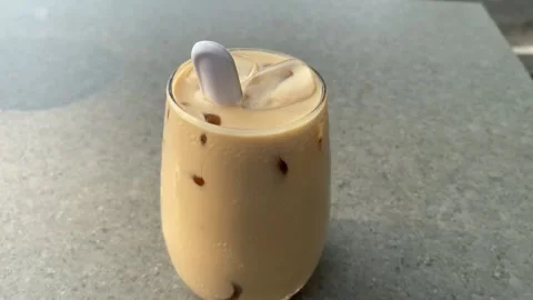 Iced coffee latte with ice cubes and a white spoon. Stock Footage 347532284