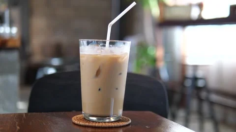Iced Coffee in Plastic Cup on Cafe Table with Natural Light and Cozy Background Video stock 325236475