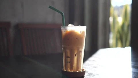 Iced Coffee in Plastic Cup on Cafe Table with Natural Light and Cozy Background Video stock 325236908