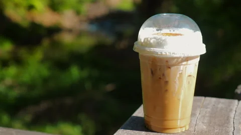 Iced coffee in plastic cup with whipped cream, placed on wooden table, Stock Footage 284757473