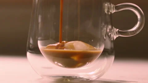 Iced Coffee Pouring on Ice Cubes in Clear Mug in Slow Motion. Video stock 340822876