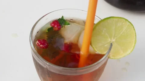 Iced fruit tea or cold berry drink in clear glass with mint leaf 動画素材 168018987