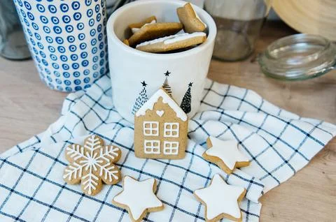 Iced gingerbread cookies on a checked tea towel beside a Christmas mug Stock Photos