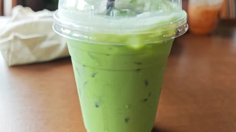 Iced Green Tea Matcha Latte in Plastic Cup with Dome Lid. Stock Footage 340487795
