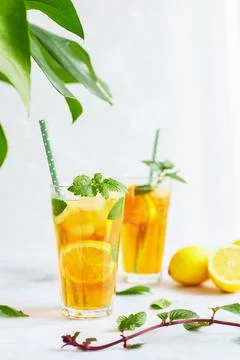 Iced iced tea in a glass with a straw, mint leaf and lemon slices inside. Cool Stock Photos