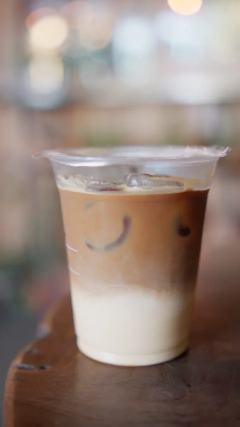 Iced latte in a plastic cup with milk and ice layers Stock Footage 346279999