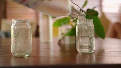 Iced lemonade poured into two clear glasses from a bottle in hipster cafe on Stock Footage 269492547