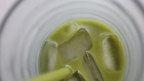 Iced matcha drink with melting ice cubes in a glass Видео 344044024