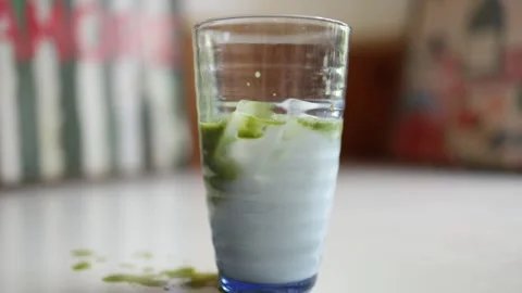 Iced matcha latte mixing with cold milk and ice in a glass Vídeos de archivo 344043981