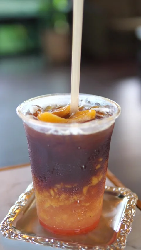Iced peach coffee in a plastic cup with straw on table in cafe Video stock 320768938