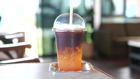 Iced peach coffee in a plastic cup with straw on table in cafe Stock Footage 320768941